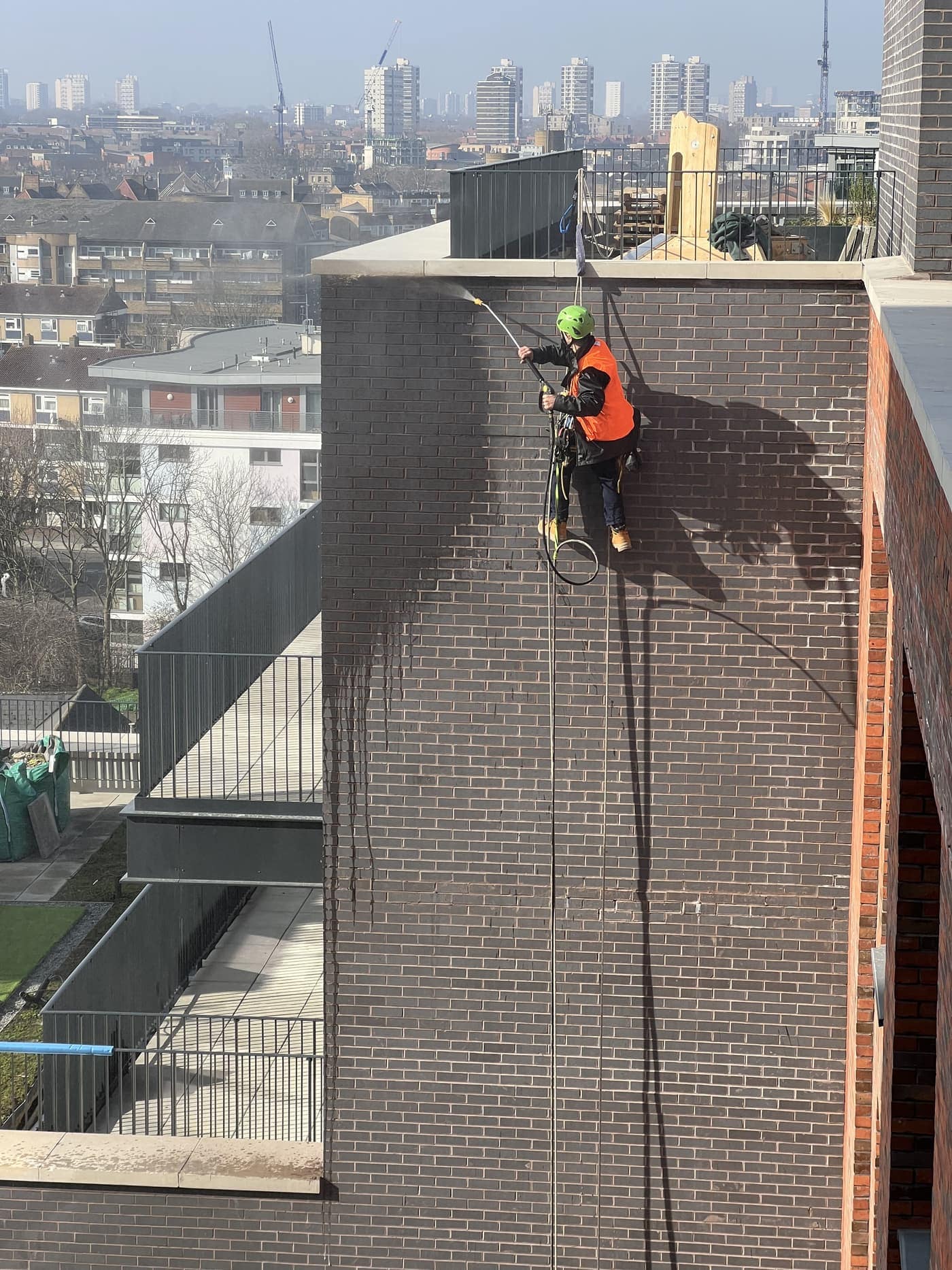 A BOVI Access technician descending a dark, weathered masonry elevation on rope